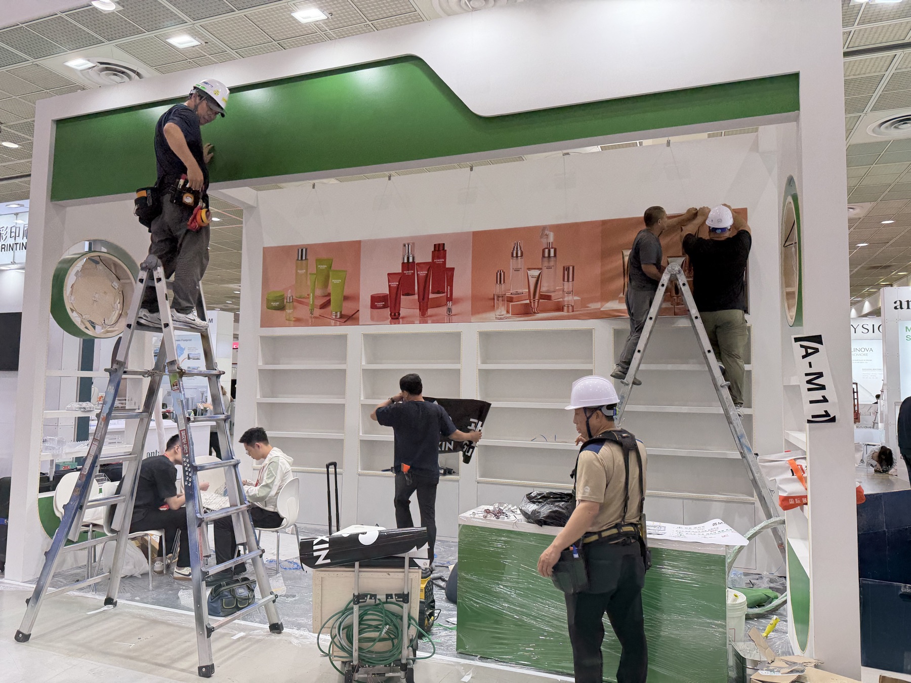 韩国展馆内多名施工人员使用梯子安装绿色展位